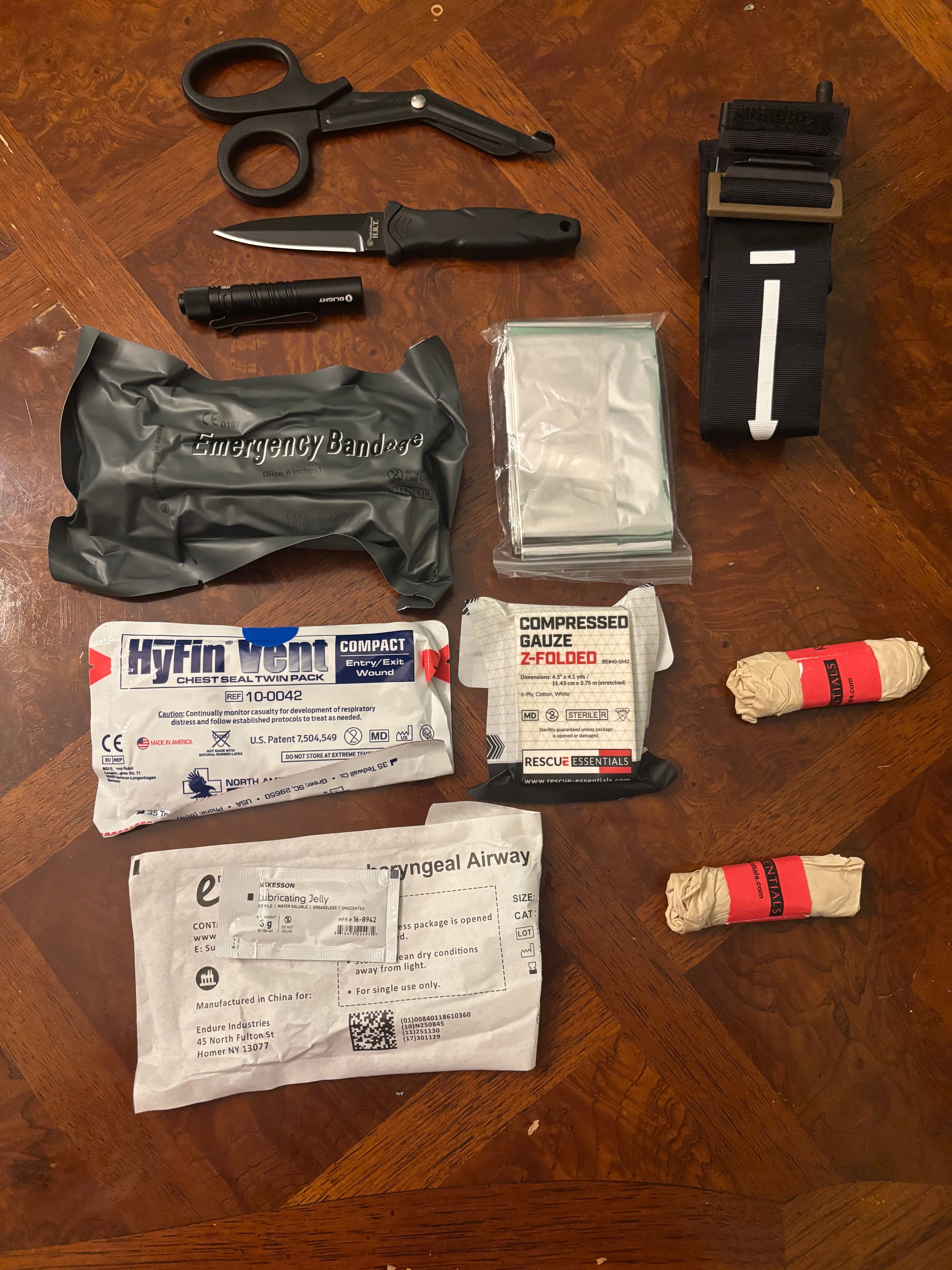 Contents of the kit. 7.5 in trauma shears, your choice of fixed or folding knife, flashlight, tourniquet, 6 in pressure dressing, Mylar blanket, pair of vented occlusive dressings, wound packing gauze, two pairs of nitrile gloves, and nasopharyngeal airway with lubricating jelly.